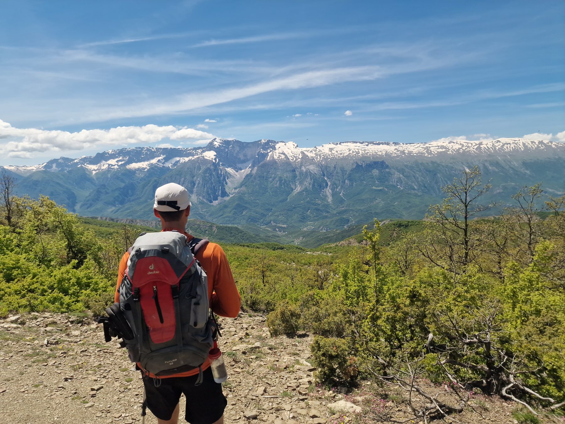 A hiker faces the snow-capped range